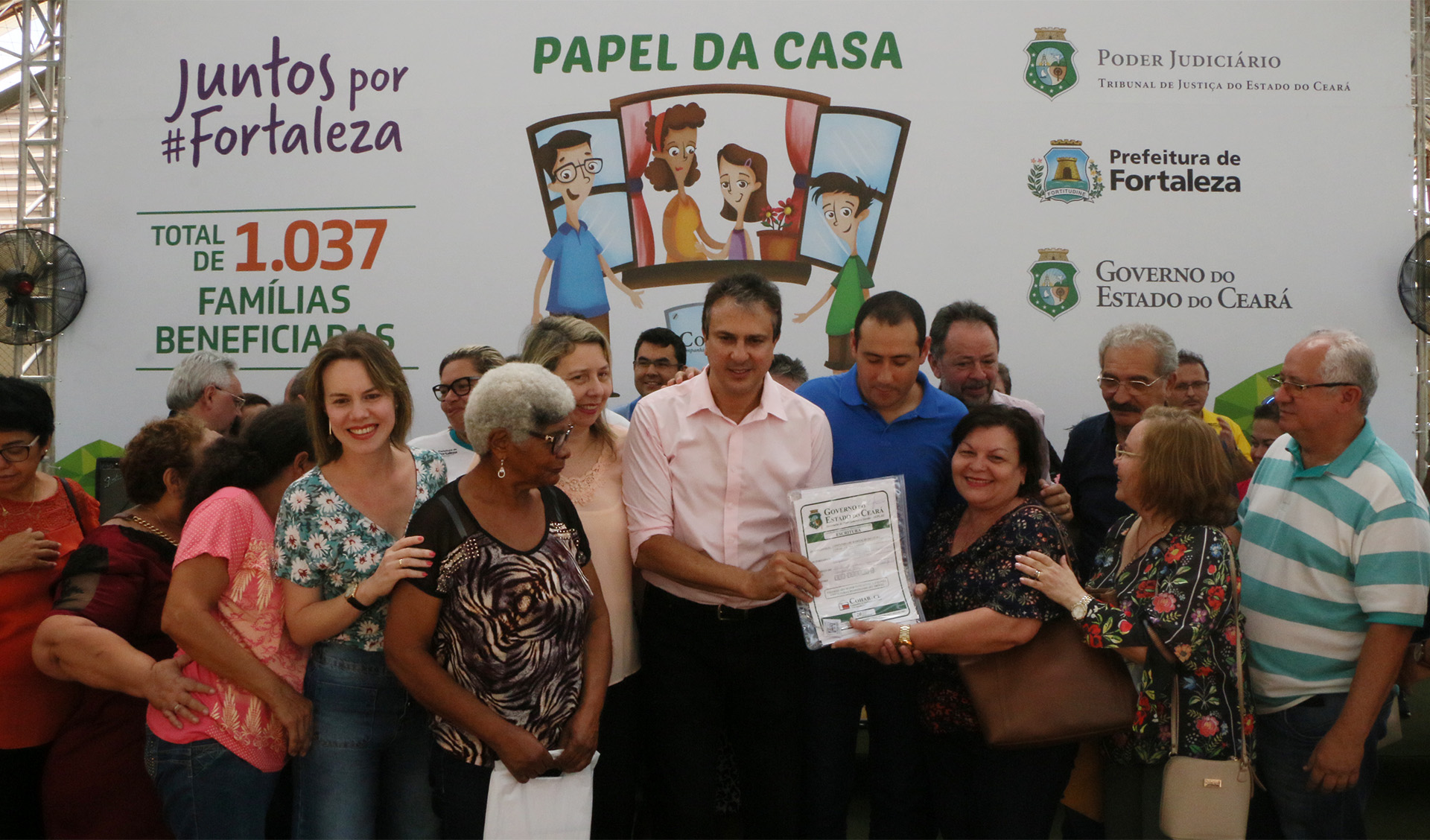 governador camilo santana abraça mulher que recebe certificado do papel da casa